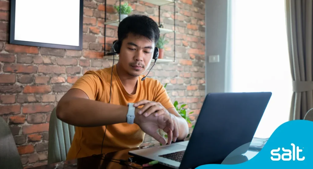 Top freelance trends for 2026 2 Man sitting at his home desk in front of his laptop looking at his watch