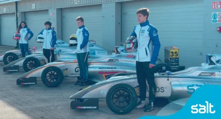 McKenzy Cresswell and team standing beside F1 race cars.