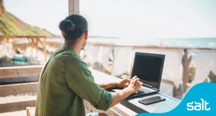 Man working remotely on his laptop at a cafe near the beach.