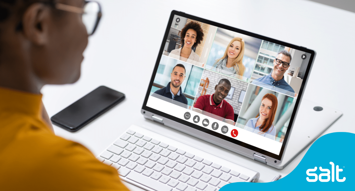 Remote employees having a virtual meeting together - can see one employee on a laptop showing another 6 employees on the call