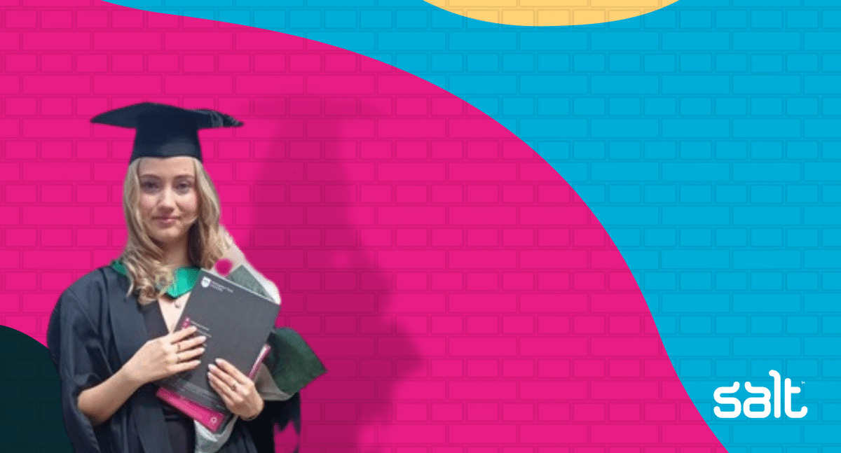 Lara-Michelle Noack in graduation gear in front of Salt's wall