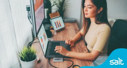 Woman sitting at a desk analysing data on digital devices.