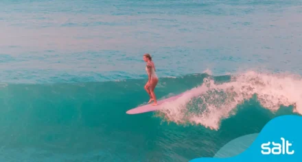 Woman surfing in the ocean on a longboard.