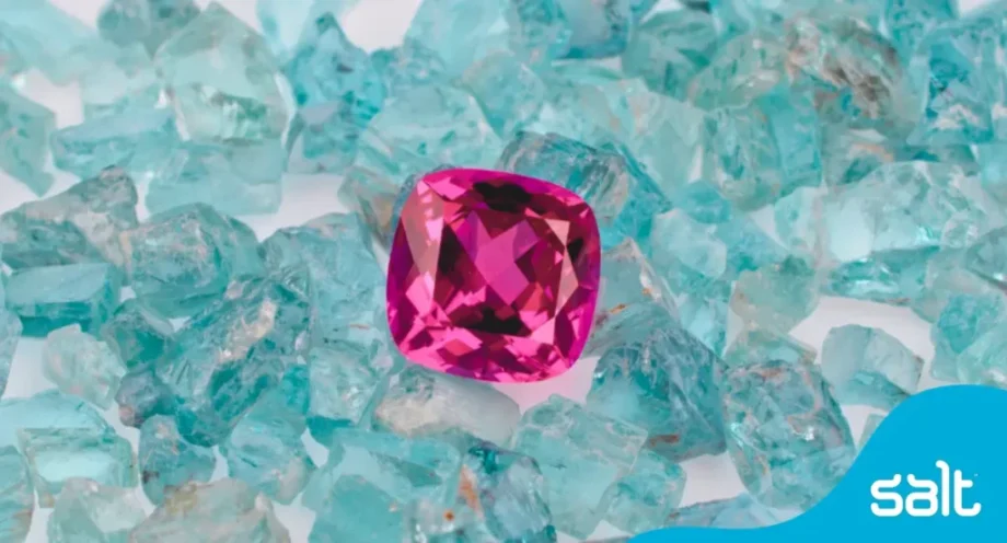 Discover your hidden gems: unleashing employee potential 1 Close up of a pink gemstone in a pile of blue glass pieces.
