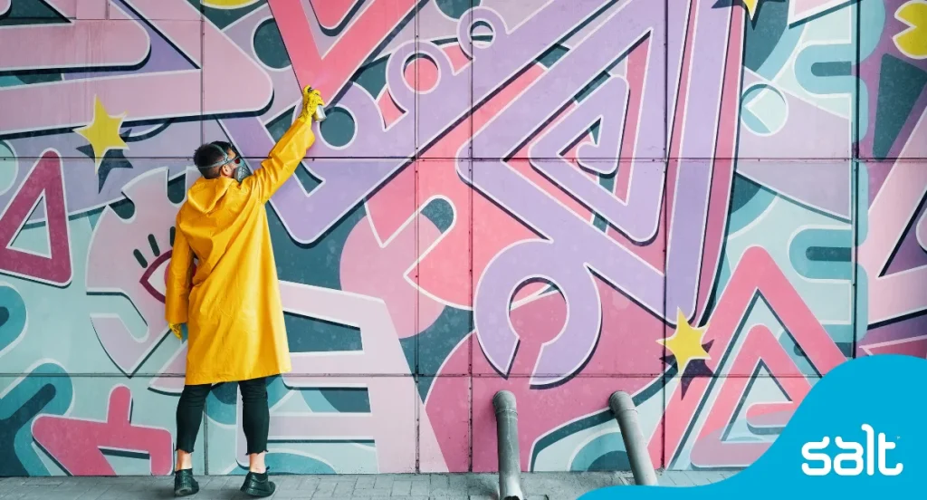 A man in yellow painting a purple mural to showcase how onboarding must paint the best picture of your company