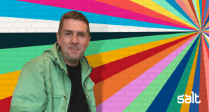Chris Sanders, Founder of Right Aligned, in front of Salt's colourful wall of fame
