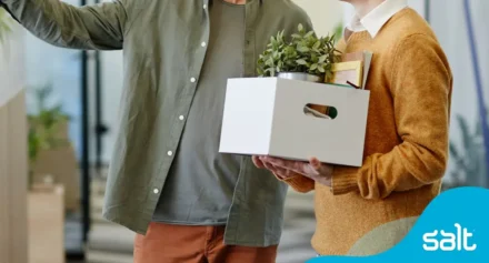 A new employee with a box of personal belongings being introduced to the workspace, representing the first day at work.