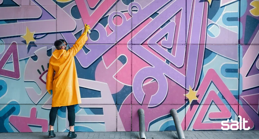 A man in yellow painting a purple mural to showcase how onboarding must paint the best picture of your company