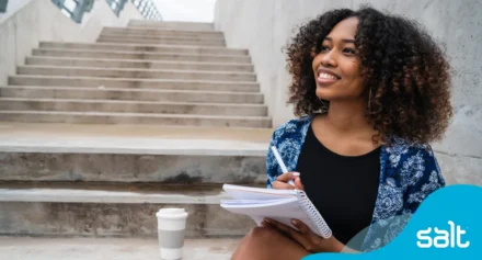 a woman sitting on stairs holding a notebook and pen
