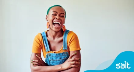 Woman proudly smiling wearing yellow shirt and dungarees