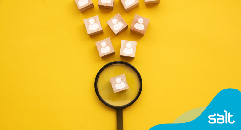 Magnifying glass focusing on wooden blocks with icons, symbolising targeted digital design recruitment and hiring practices by Salt