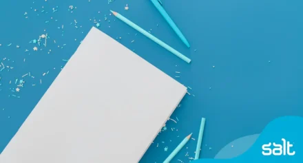 Empty page with pencils beside it on a blue background.