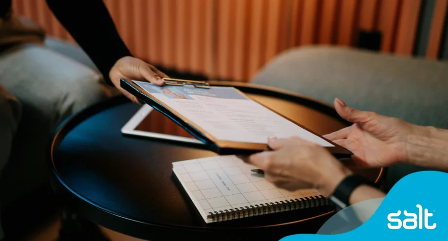 How to write a CV: top tips for 2025 1 Close up of someone handing their CV over to interviewee.