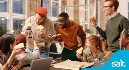 Team of people cheering with slices of pizza looking happy