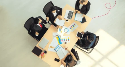 Top view of business colleagues sat around a large office desk working with data