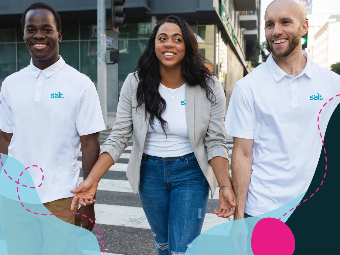 Three team members walk across a city street, smiling