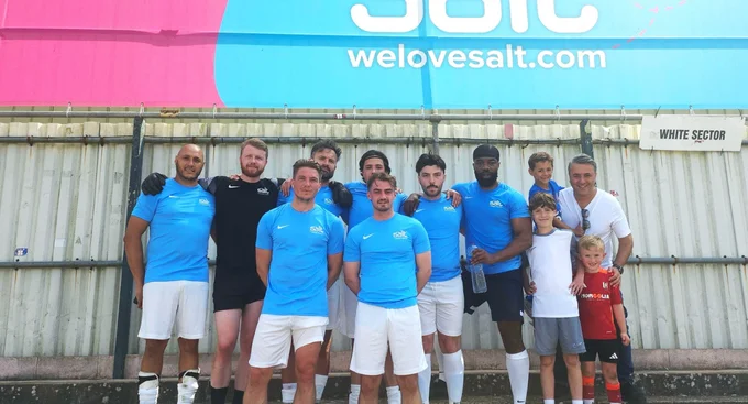 Salt football team posing together after a match, with children and supporters