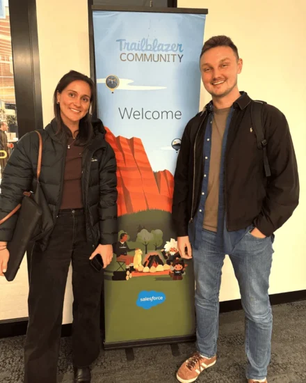 Two colleagues smiling in front of a "Trailblazer Community" Salesforce welcome banner