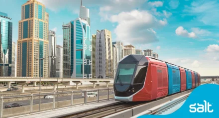 Tram on railway with Dubai city buildings in the background.