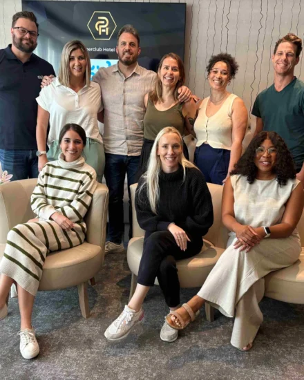 A group of ten team members pose together indoors, smiling during a leadership strategy day, with some seated and others standing behind them.