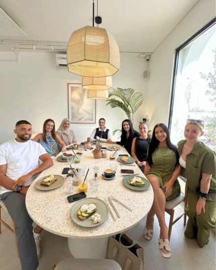Salt team members enjoying a team lunch around a large table in a bright, modern café.