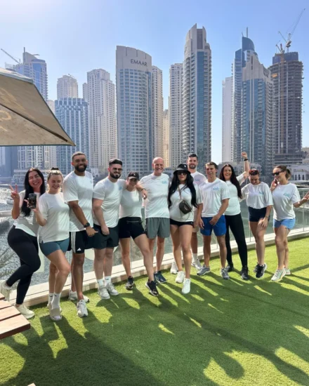 Group of Salt team members in athletic wear posing outdoors at Dubai Marina with skyscrapers in the background, after a running club session.