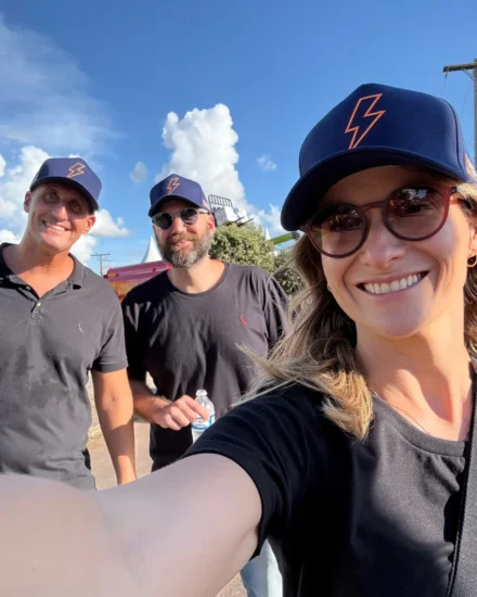Three people smiling outdoors taking a selfie, wearing matching outfits at the Agribusiness Fair