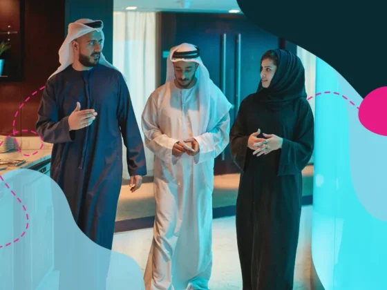 three Emirati employees walking in an office talking to one another, representing Emiratisation