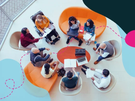 Top view of a large diverse group of people sitting at a round table in an office.