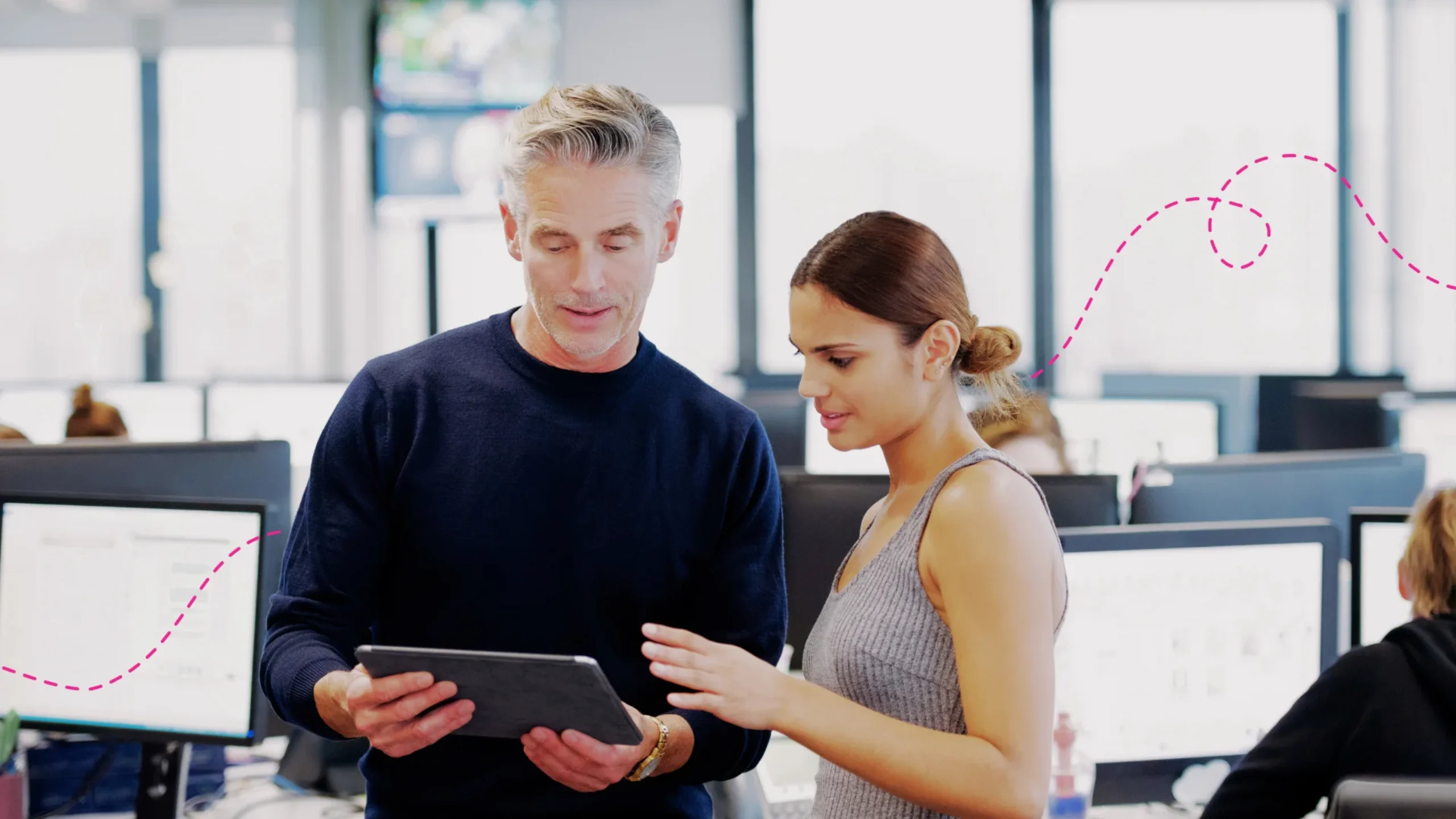 Two people looking at a tablet working together in a office
