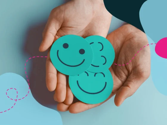 Hands holding cutouts of smiley faces.