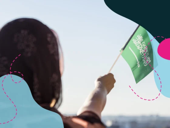 Close up of Saudi woman in traditional clothing waving the Saudi flag.