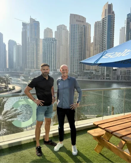 Two men, including Salt CEO, Elliot Dell and the UAE Director, Richard Smith standing on a terrace overlooking Dubai Marina with high-rise buildings in the background.