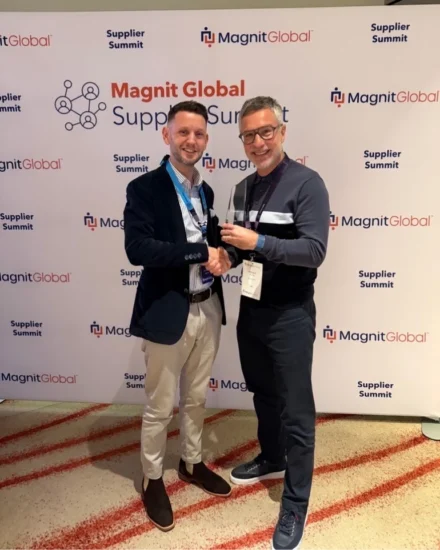 Two men, including Salt's UK Director, Richard Norris, smiling and shaking hands while holding an award in front of a Magnit Global Supplier Summit backdrop.
