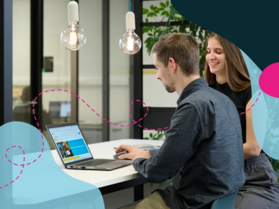 Two people in an office looking at a laptop.