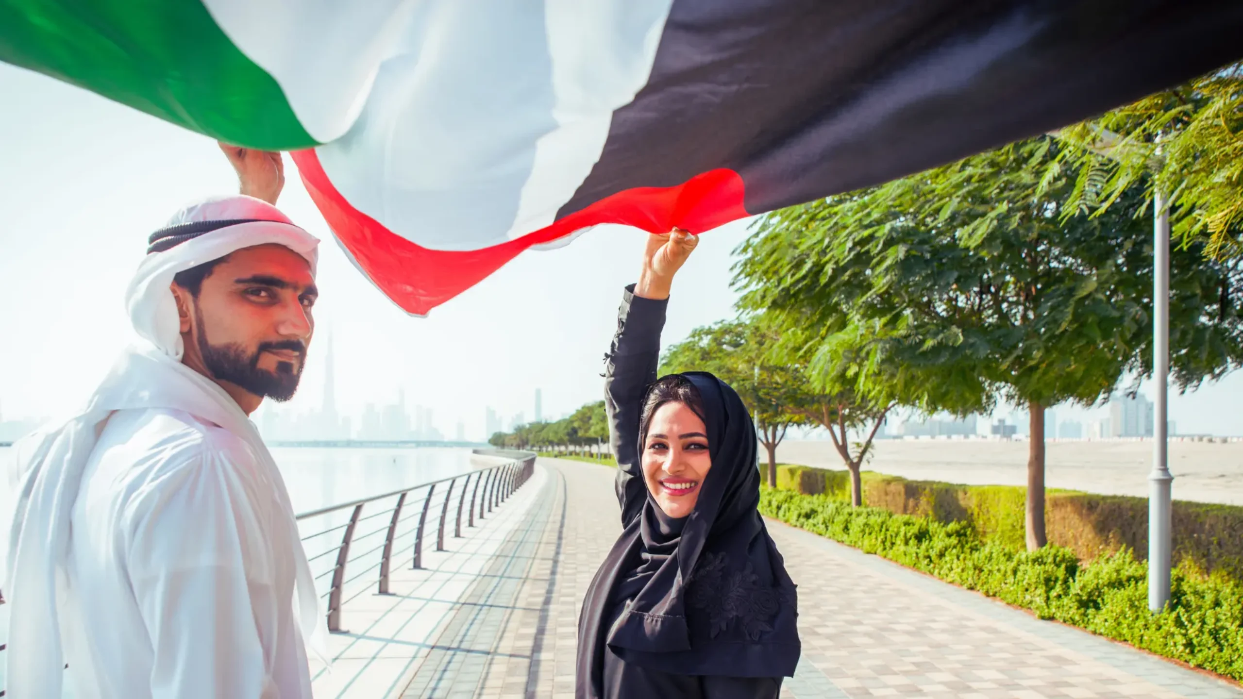 man and woman holding UAE flag